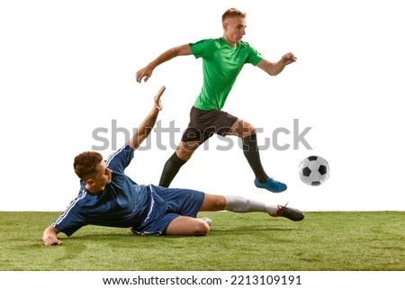 Soccer football players tackling for the ball on grass flooring over white background. Concept of sport, action, competition, football match. Athletes in action, movement at game.