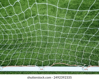 Soccer goal net backstop on a green turf field. Straight on view with white netting pattern and metal posts. - Powered by Shutterstock