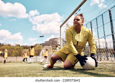 Soccer goalie catching the ball while having sports training on playing filed. - Powered by Shutterstock