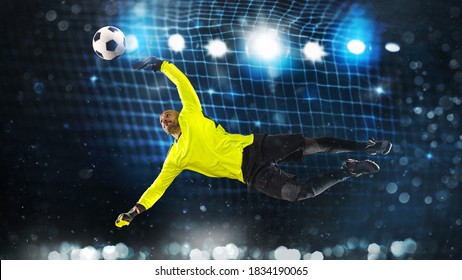 Soccer goalkeeper, in fluorescent uniform, that makes a great save and avoids a goal on a dark blue background - Powered by Shutterstock