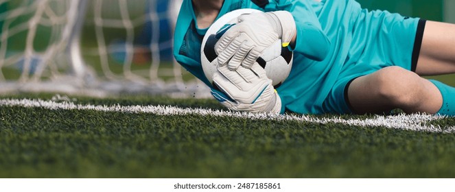 Soccer goalkeeper holding a soccer ball tight to the chest. Football training for young goalies  - Powered by Shutterstock