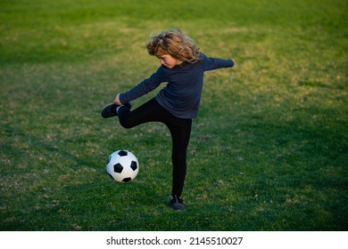 Soccer Kid. Kids Play Football On Summer Stadium Field. Little Child Boy Kicking Ball. Boy Kicking Football Ball. Young Boy With Soccer Ball Doing Flying Kick.