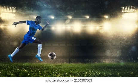 Soccer player in blue uniform sprinting fast with the ball at the stadium - Powered by Shutterstock