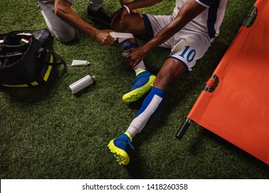 Soccer player injured knee during the game. Sport Doctors provide first aid to player on a professional football field. Close up - Powered by Shutterstock