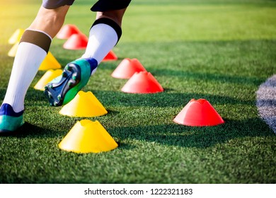 Soccer player Jogging and jump between cone markers on green artificial turf for soccer training. Football or Soccer Academy.