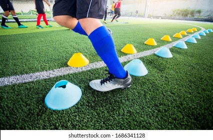 Soccer player Jogging and jump between cone markers on green artificial turf for soccer training. Football or Soccer Academy. - Powered by Shutterstock