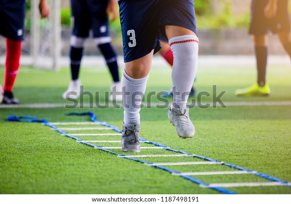 Soccer player Jogging and\
jump between marker for football training. Ladder Drills Exercises\
for Football Soccer team. Young player exercises on ladder\
drills.