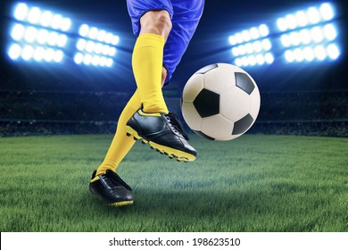 Soccer player kicking the ball on the field at night