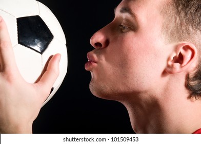 soccer player is kissing the ball in dark