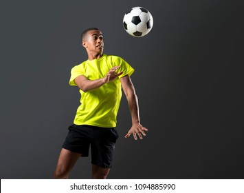 Soccer player man with dark skinned playing hitting head on dark background - Powered by Shutterstock