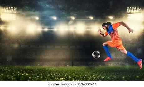 Soccer player in orange and blue uniform sprinting fast with the ball at the stadium