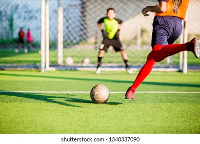soccer player run to shoot ball at penalty kick to goal with blurry goalkeeper background, concept of making goals and protection