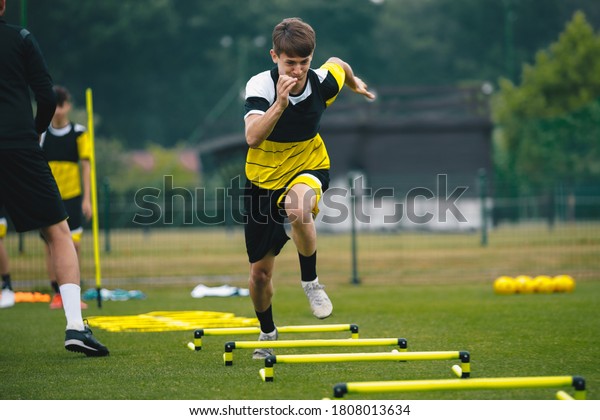 Soccer player running fast and ladder skipping.\
Teenagers on soccer training camp. Boys practice football witch\
young coach. Junior level athletes improving soccer skills on\
outdoor training