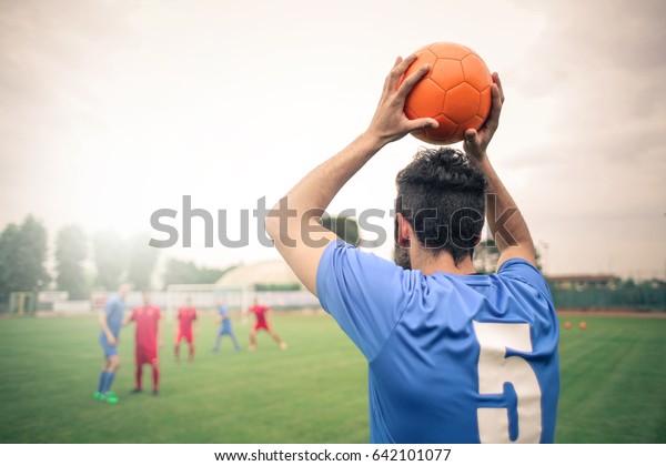 Soccer player throwing the\
ball in\
