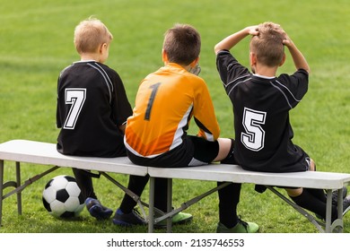 Soccer Players Sitting On Sideline Bench. School Football Team. Youth Soccer Players Sitting Together On Substitute Bench And Watching Match