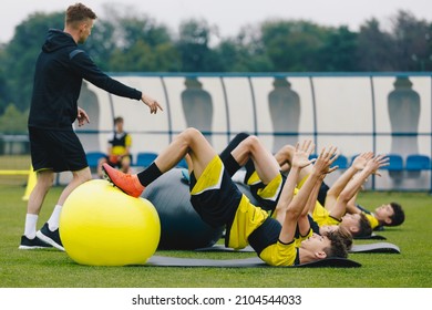 Soccer Players: Stretching Session With Physiotherapist. Youth Sports Team On Recovery Session After League Match. Football Players Warming Up On Grass Stadium Field