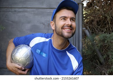 Soccer Playing In Blue Shirt And Cap Holding Silver Ball