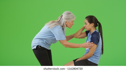 Soccer referee checks that the injured player is not concussed on green screen - Powered by Shutterstock