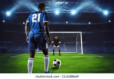 Soccer scene at night match with player in blue uniform kicking the penalty kick