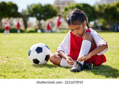 Soccer, sports and girl tie her shoes in training practice for fitness, wellness and youth development. Exercise, workout and goals with child and soccer ball on football field for games match - Powered by Shutterstock