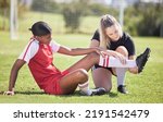 Soccer, sports and injury of a female player suffering with sore leg, foot or ankle on the field. Painful, hurt and discomfort woman getting her pain checked out by athletic trainer on the pitch.