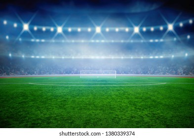 Soccer stadium with illumination, green grass and night  blurred sky - Shutterstock ID 1380339374