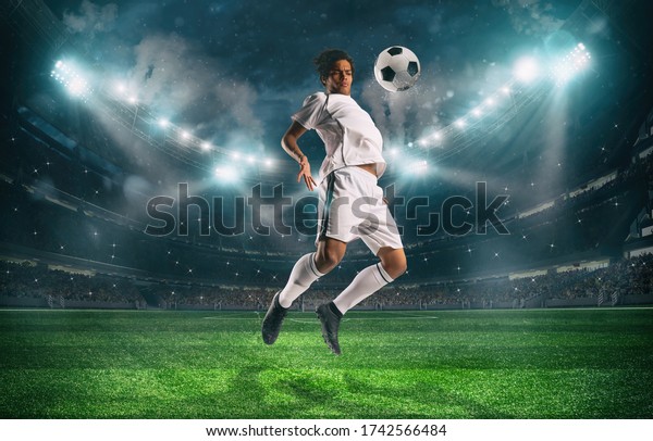 Soccer striker stops the ball with an
acrobatic jump at the stadium during a night
match
