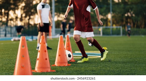 Soccer Training Class. Legs of Children on Football Lesson. Kids Practicing Soccer Skills on School Grass Field. Boy Running Next to Orange Training Cone in Practice Drill - Powered by Shutterstock