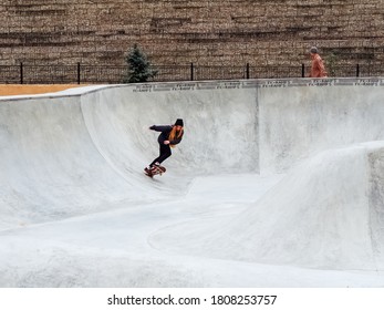 Sochi, Russia - 26 December 2019. Red-haired girl in black hat performs a trick on a skateboard in a skatepark