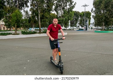 Sochi. Russia . June 5, 2022.Attractive man riding a kick scooter at cityscape background.