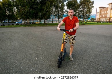 Sochi. Russia . June 5, 2022.Attractive man riding a kick scooter at cityscape background.