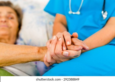 Social care provider holding senior hands in caring attitude - helping elderly people.