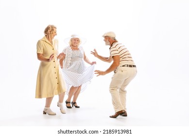 Social Dances. Handsome Senior Man And Two Charming Women In Vintage Retro Style Outfits Dancing Isolated On White Background. Concept Of Relations, Family, 1960s American Fashion Style And Art.