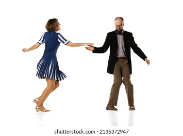 Social dancing. Couple of dancers, young man and woman in vintage retro style outfits dancing swing dance isolated on white background. Timeless traditions, 60s, 70s fashion style.