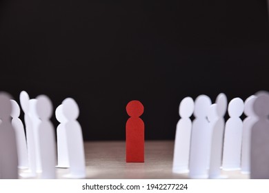 social discrimination concept with many little white paper men around a different one on wooden base and dark background front view - Shutterstock ID 1942277224
