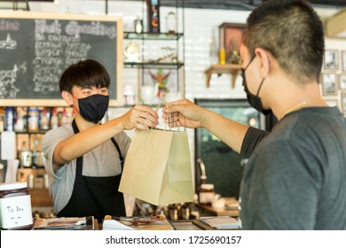 Social distance conceptual waiter giving takeaway bag to customer at cafe. - Shutterstock ID 1725690157