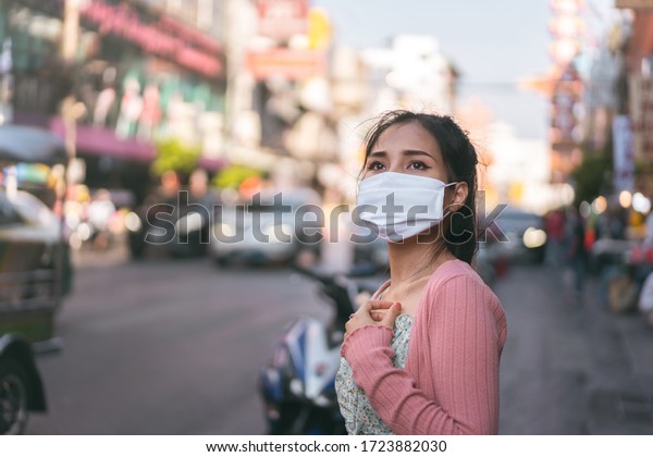 Social distance and virus\
protect at outdoor area concept. Asian adult woman tan skin wear\
mask on face. Background chinatown landmark destination. Bangkok,\
Thailand.