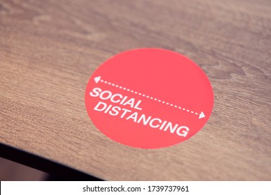 Social Distance Word Sticker On The Table In Restaurant.Social Distancing Instruction Against The Spread.New Normal Reopen Mall, School.Social Distancing In The Workplace During Coronavirus COVID-19.