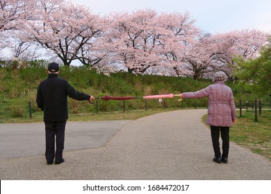 Social distancing (6 feet / 2 meters) to avoid the spread of coronavirus (COVID-19). Two people stand apart holding two umbrellas. A new concept along with elbow bumping. New normal.