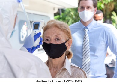 Social distancing concept. Officer wearing a respirator mask to use infrared forehead thermometer to check fever body temperature for virus symptoms. Respiratory diseases such flu covid19, coronavirus - Powered by Shutterstock