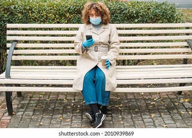 Social Distancing. Covid Impact. Pandemic Loneliness. Young Overweight Woman With Curly Hair In Protective Face Mask Phone Texting On Bench In City Street.