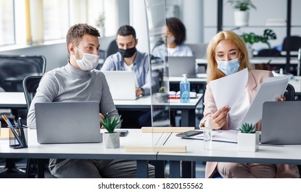 Social distancing and document management during coronavirus outbreak. Millennial guy and lady in protective masks discuss work issues and look at papers through protective board, panorama, free space - Shutterstock ID 1820155562