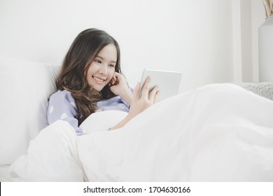 Social Distancing. Happy Young Asian Pretty Woman Video Call Chat On Digital Mobile Tablet On Bed At Home In Morning, Quarantine, Facetime Connection, Internet And Social Network Technology Concept