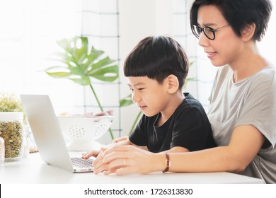 Social Distancing & Internet Parental Controls Concept, Cute Little Asian Boy Sit With Mother Using Notebook Computer. Home Based Learning, Remote, Online Classroom, New Normal, Covid-19 Pandemic.