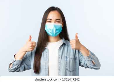 Social Distancing Lifestyle, Covid-19 Pandemic Everyday Life And Leisure Concept. Supportive Enthusiastic Asian Woman In Medical Mask Thumbs-up, Wearing PPE While Going Grocery Shopping