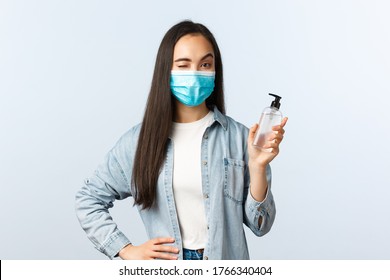 Social Distancing Lifestyle, Covid-19 Pandemic Preventing Virus Concept. Cheerful Asian Woman In Medical Mask Wink, Encourage People Use Hand Sanitizer And Wash Hands During Coronavirus