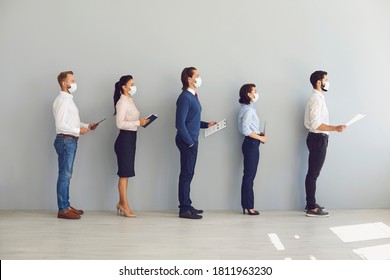 Social Distancing in Office concept. Company employees or job applicants in face masks standing in corridor. Candidates waiting for interview keeping safe distance to prevent spread of coronavirus