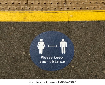 Social distancing sign on a railway station platform, keep your distance sticker with a man and a woman