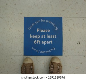 Social Distancing Sign On Store Floor To Please Keep At Least Six Feet Apart When In Line.