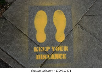 A Social Distancing Sign Outside A Shop, Showing How Far People Need To Stand Apart To Stop The Spread Of Corona Virus.